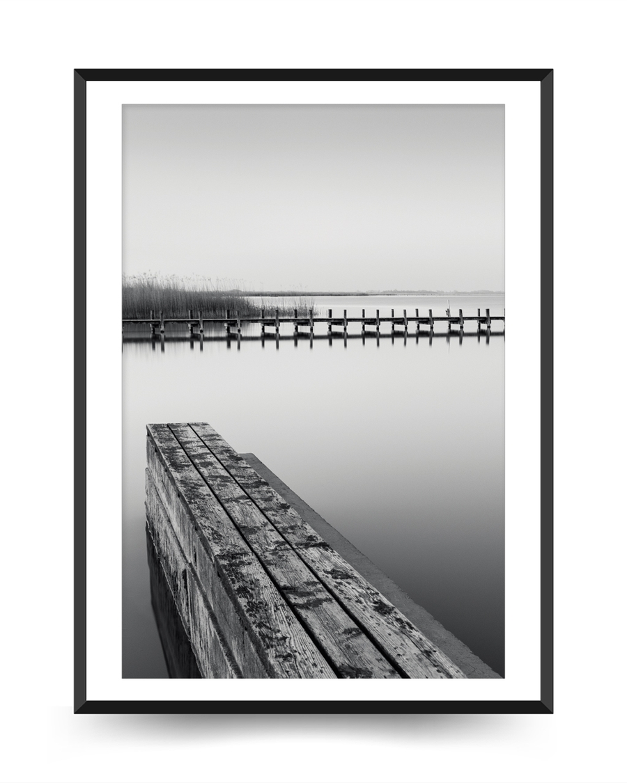 A poster of a Wooden pier reflected in calm black and white water