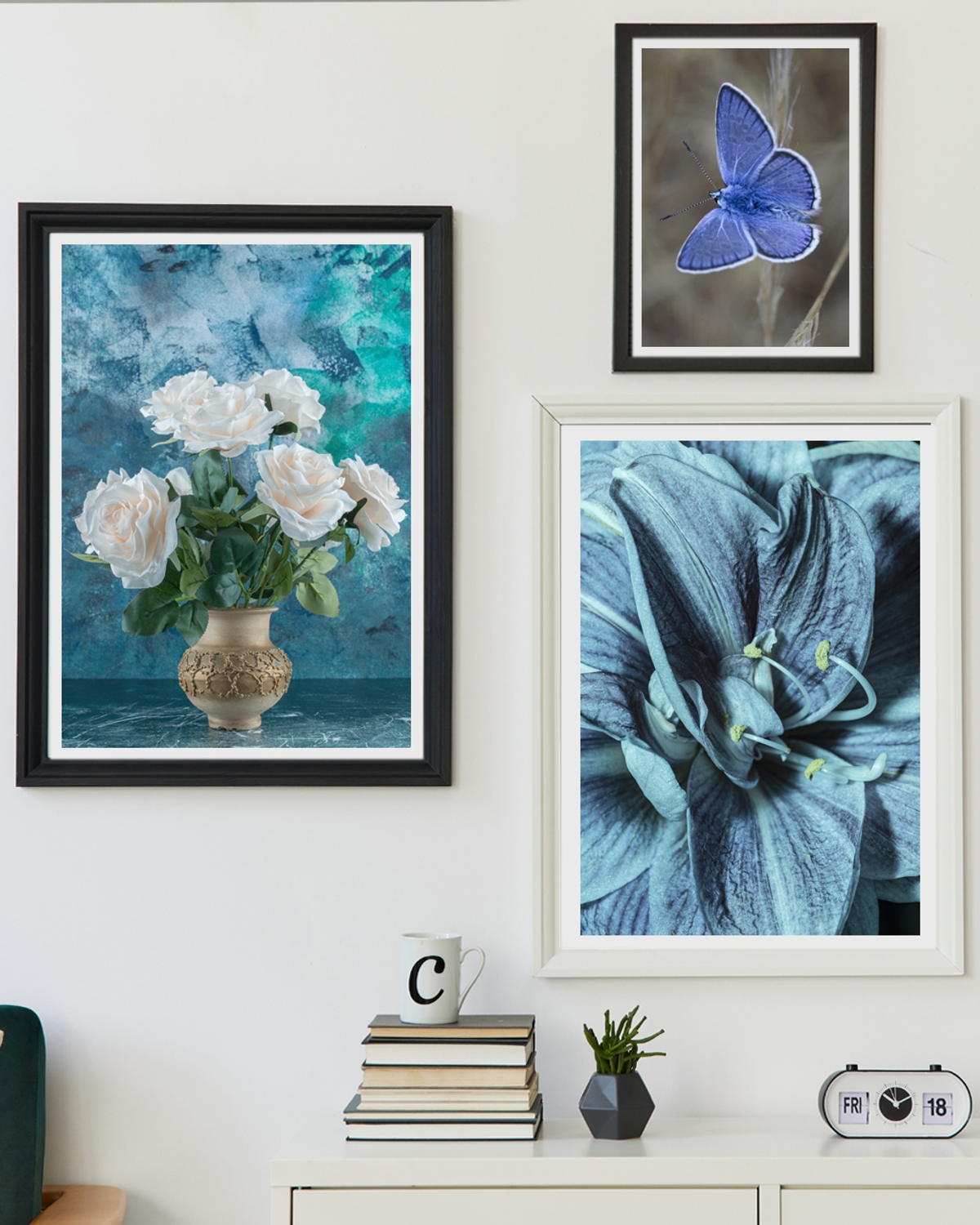 Three framed posters hanged on a white wall over a table