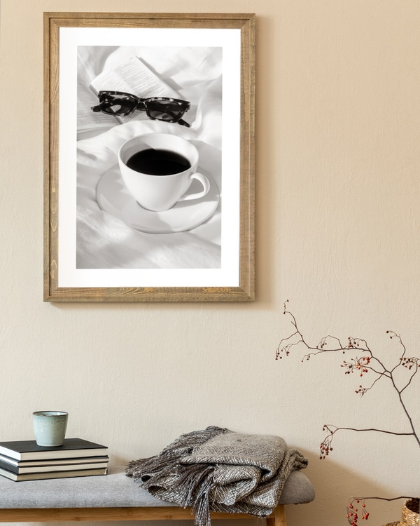 Slow Morning Coffee poster in a rustic wooden frame above a bench with folded throw