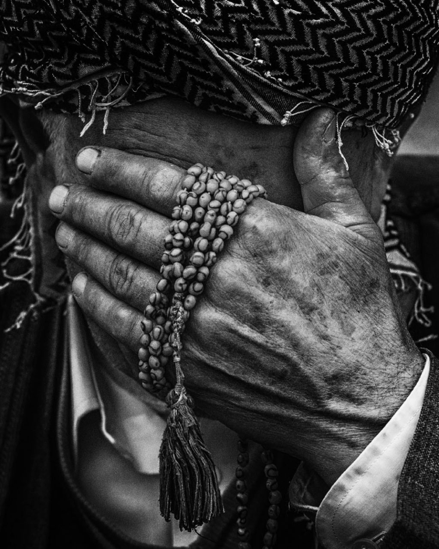 An elderly man holding his face with his left hand