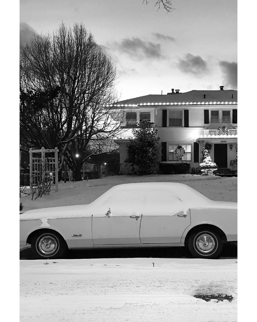 Classic car covered in snow in front house