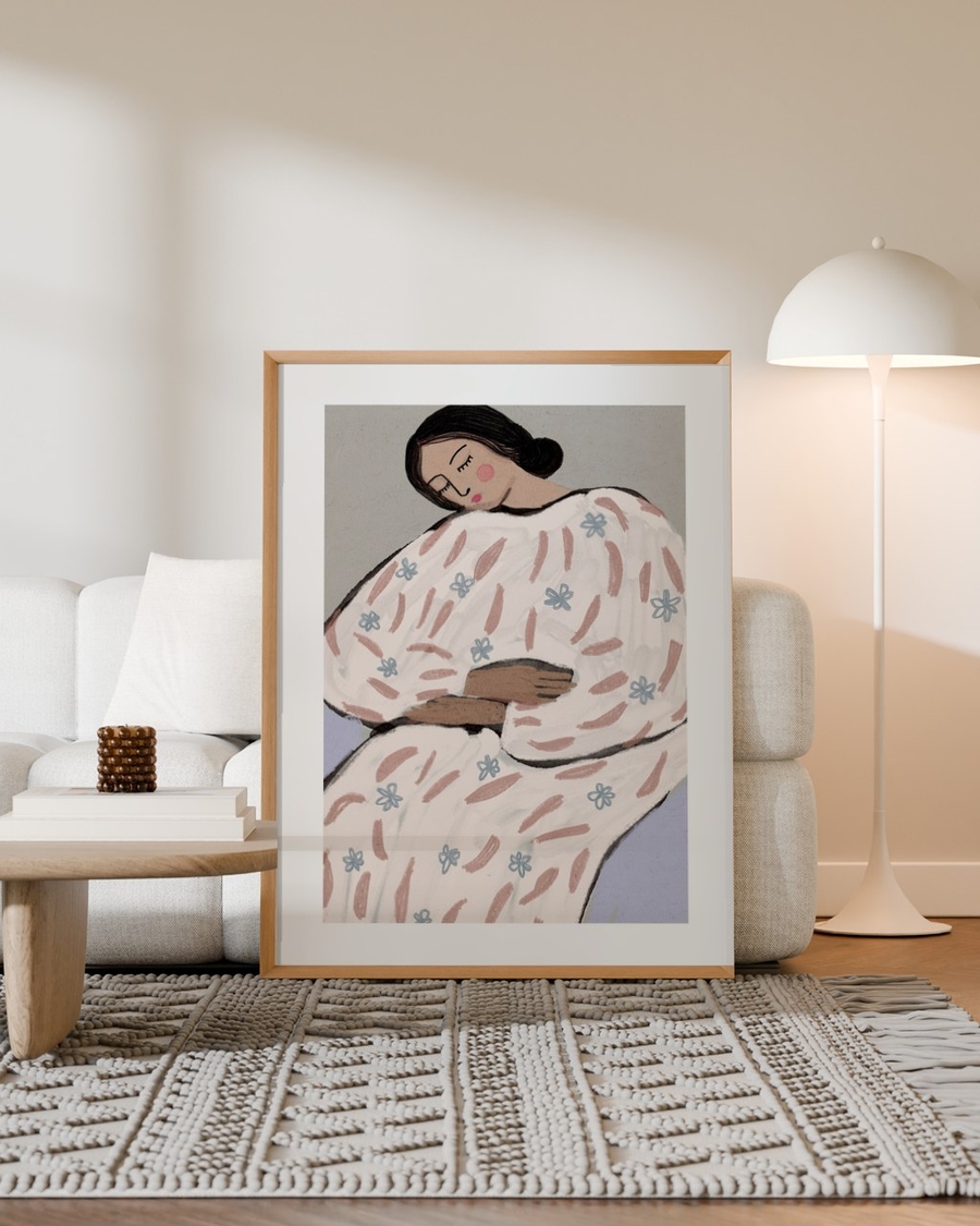Dreaming in Blossoms poster in a light oak frame leaning against a sofa in a neutral living room