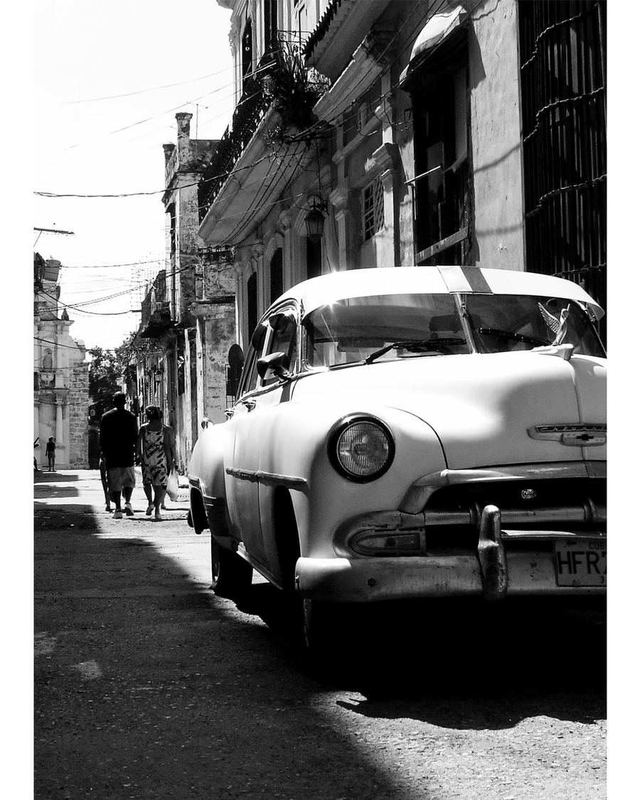 Classic car parked on narrow street with old buildings