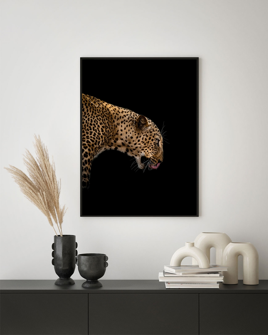 A framed poster of a focused leopard hanged over a table on a white background