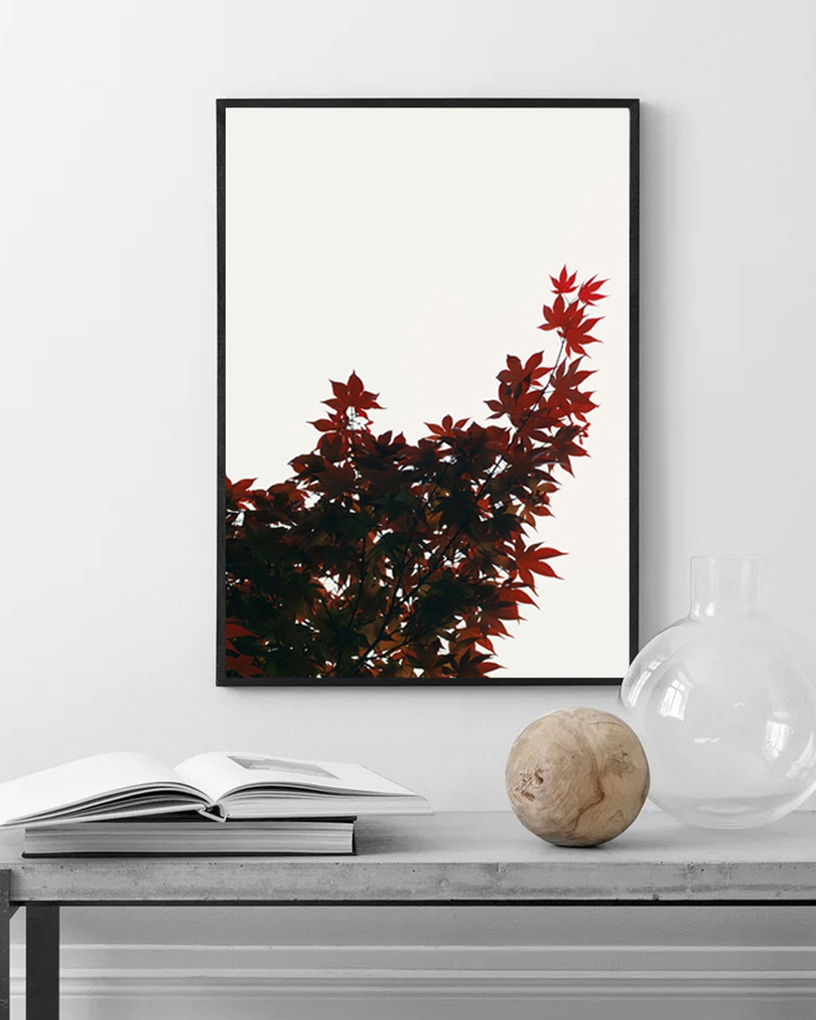Poster of a crimson maple tree leaves on a white wall over a silver table