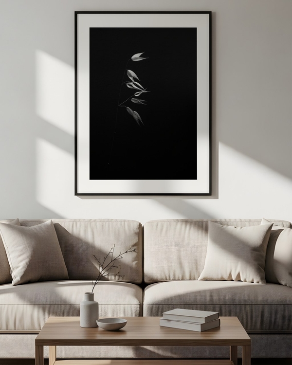 Glowing Oat Stem poster in a slim black frame above a beige sofa in a sunlit living room