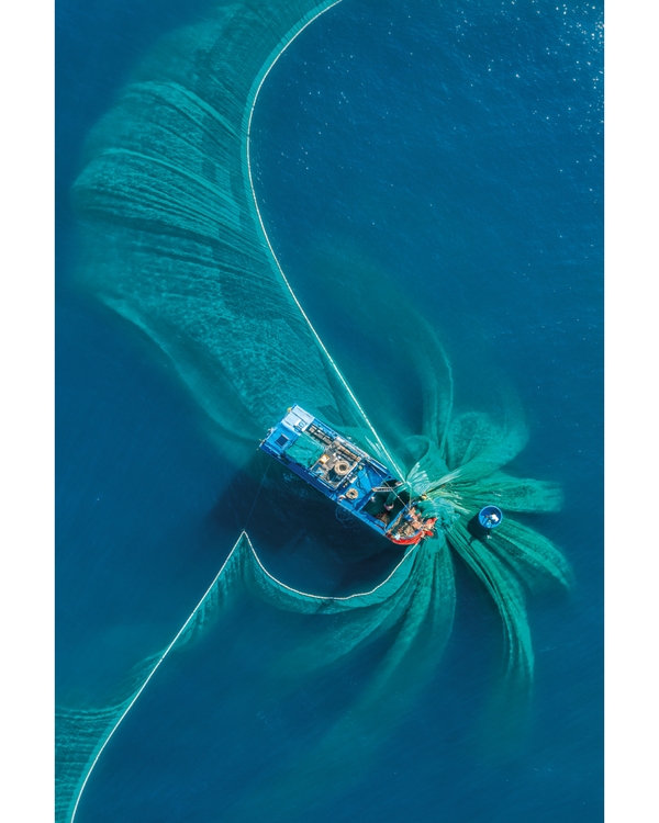 Aerial boat creating swirling patterns in blue water