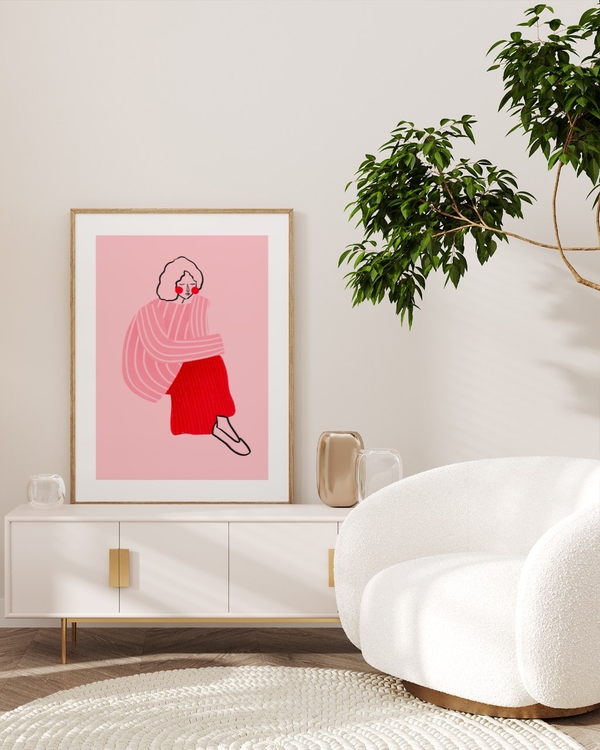 Thoughtful in Pink poster in a light oak frame leaning on a white sideboard in a bright living room