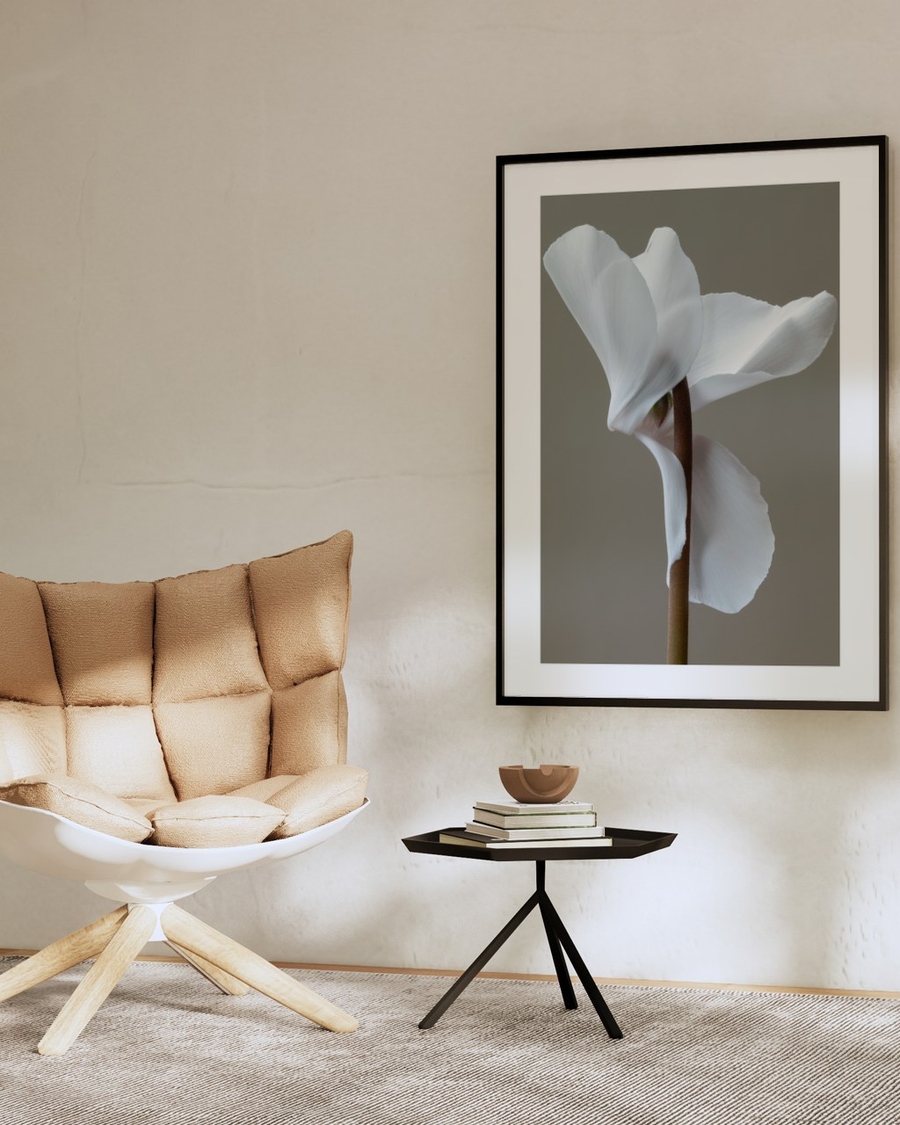 White Cyclamen Study poster in a slim black frame above a small side table in a beige minimalist living room