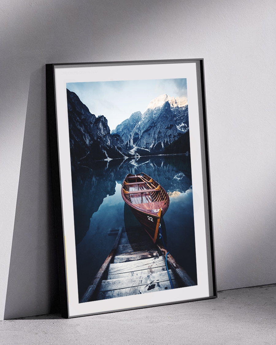 A poster of a Wooden boat moored on calm alpine lake with mountains