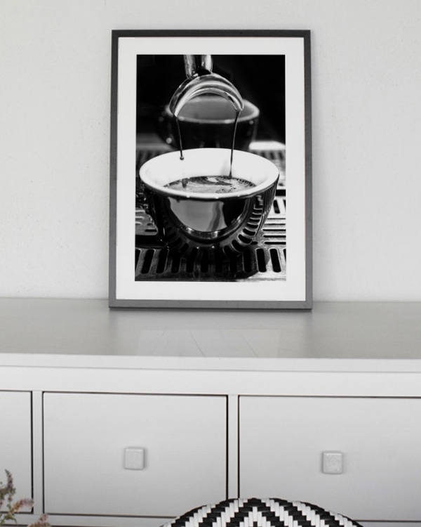 Espresso Pour poster in a slim black frame on a grey sideboard behind a dining table