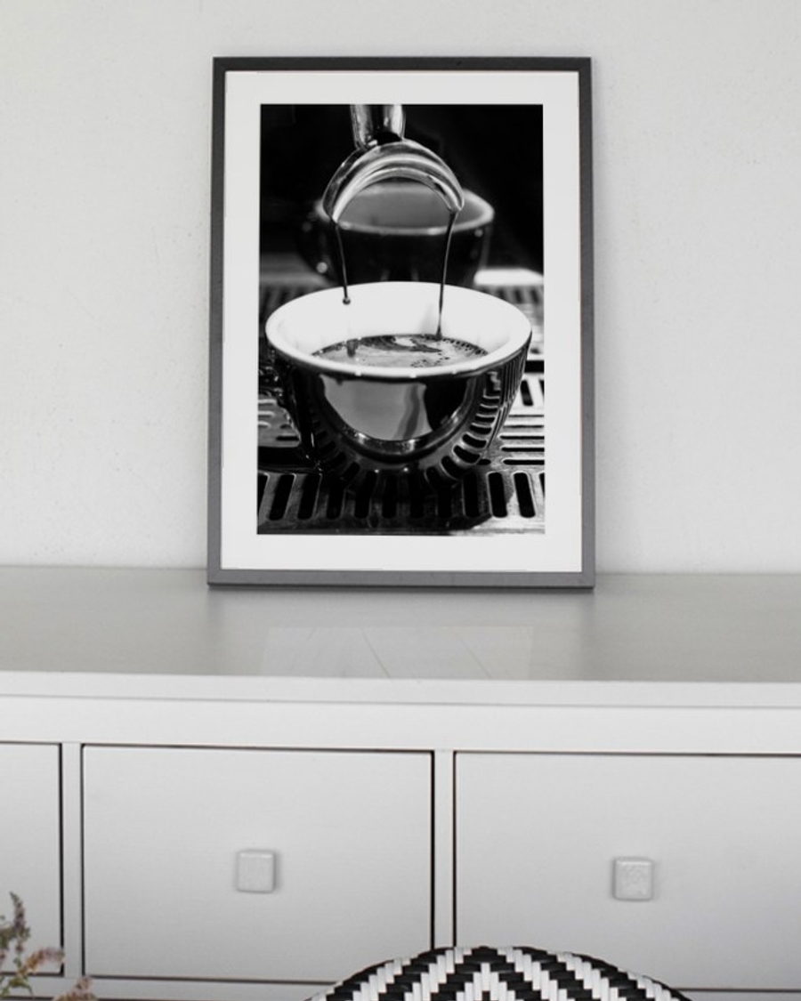 Espresso Pour poster in a slim black frame on a grey sideboard behind a dining table