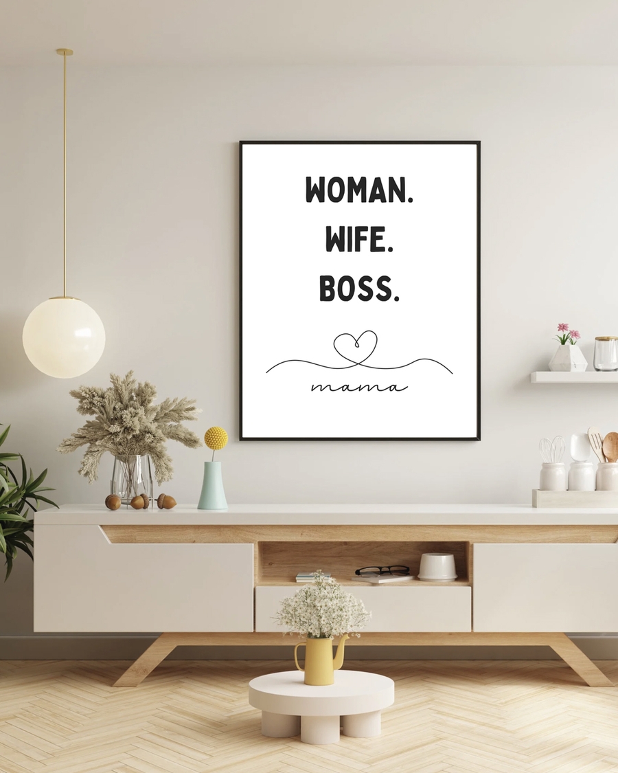 A poster of the words Woman, Wife, Boss, Mamma hanged on a beige wall over a table