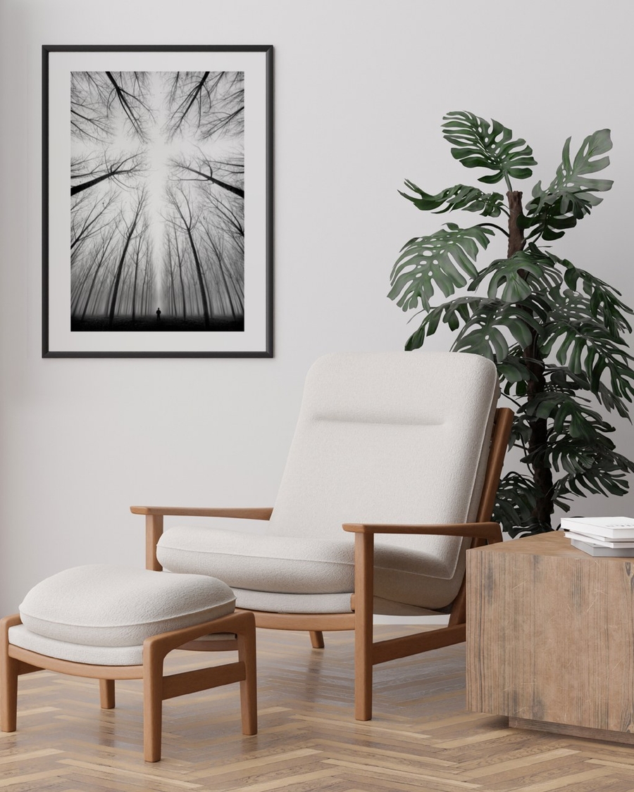 Beneath Bare Branches poster in a slim black frame above a cream armchair in a bright living room