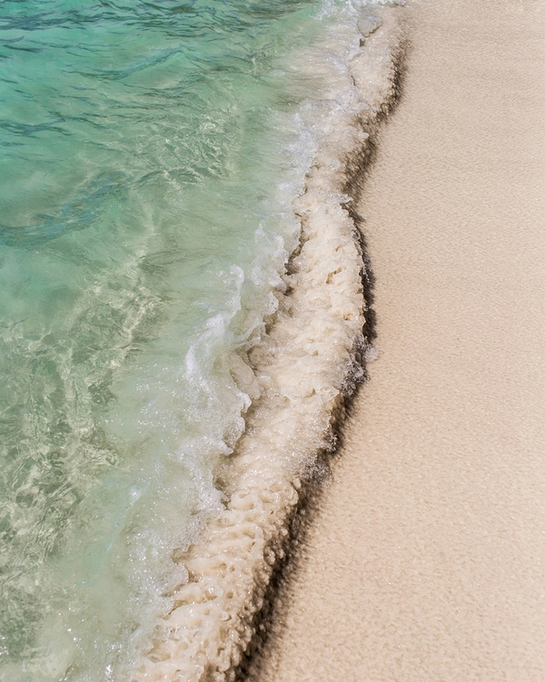 Close-up of turquoise ocean waves washing onto sandy beach