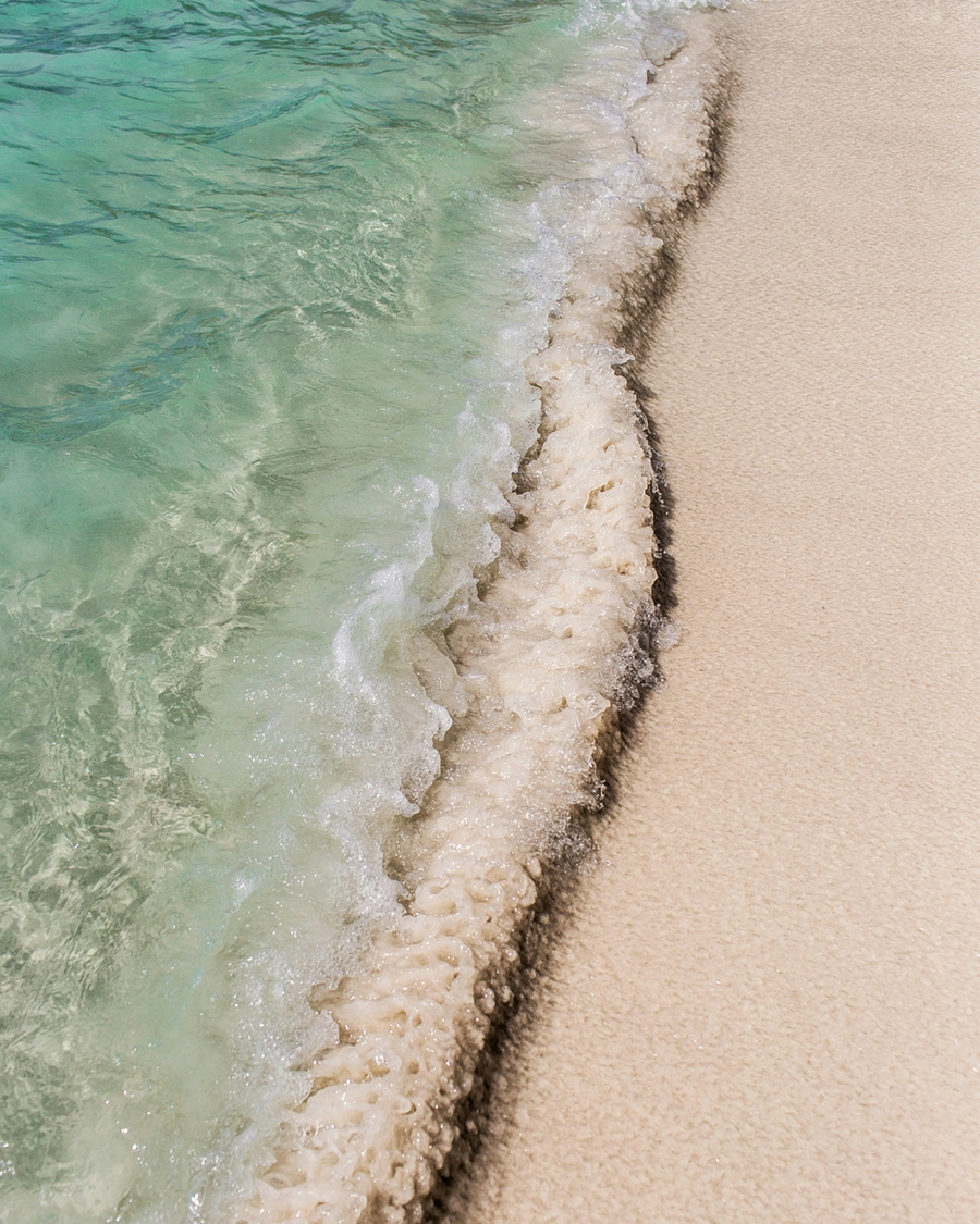 Close-up of turquoise ocean waves washing onto sandy beach