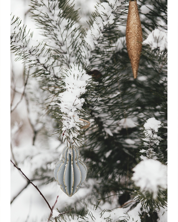 Snow-covered pine branches with elegant Christmas ornaments