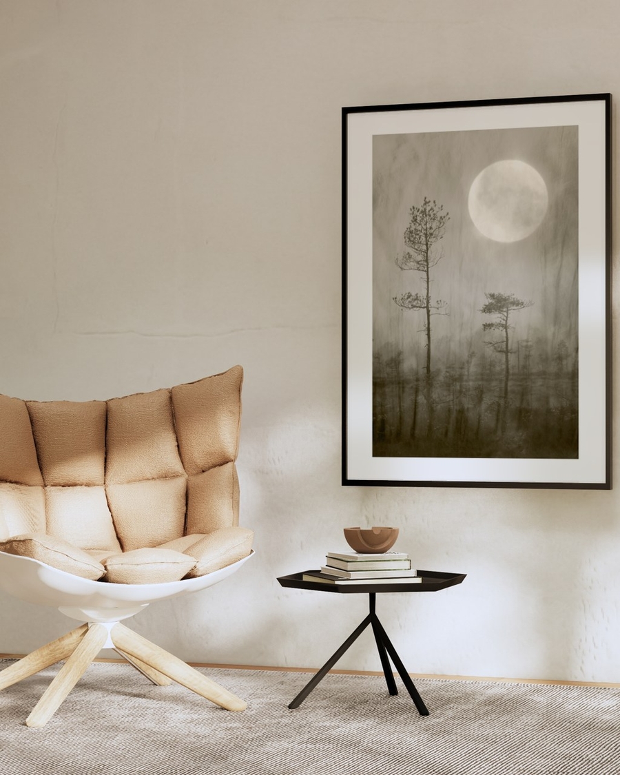 Moonlit Pines poster in a slim black frame above a small side table in a beige minimalist living room