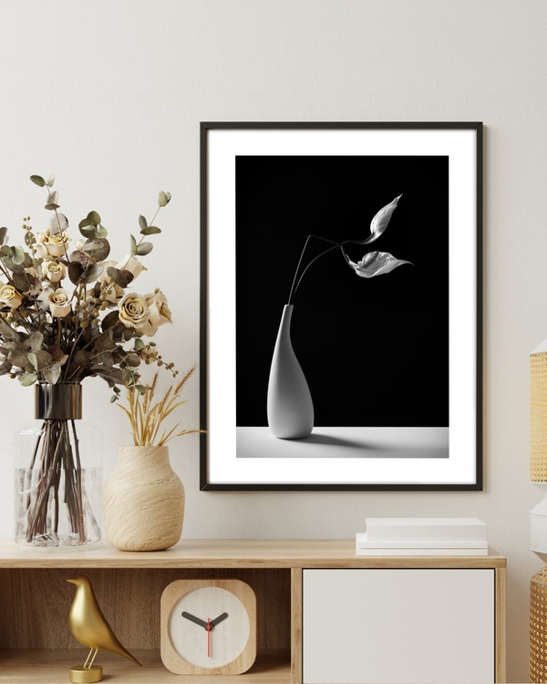 Porcelain Lily poster in a slim black frame above a wooden sideboard with dried flowers