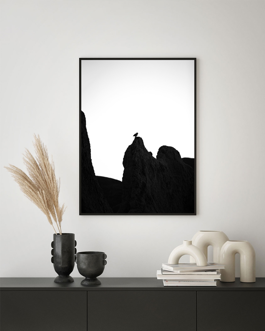 A framed poster of a lonely owl on the wall, over a black cabinet.