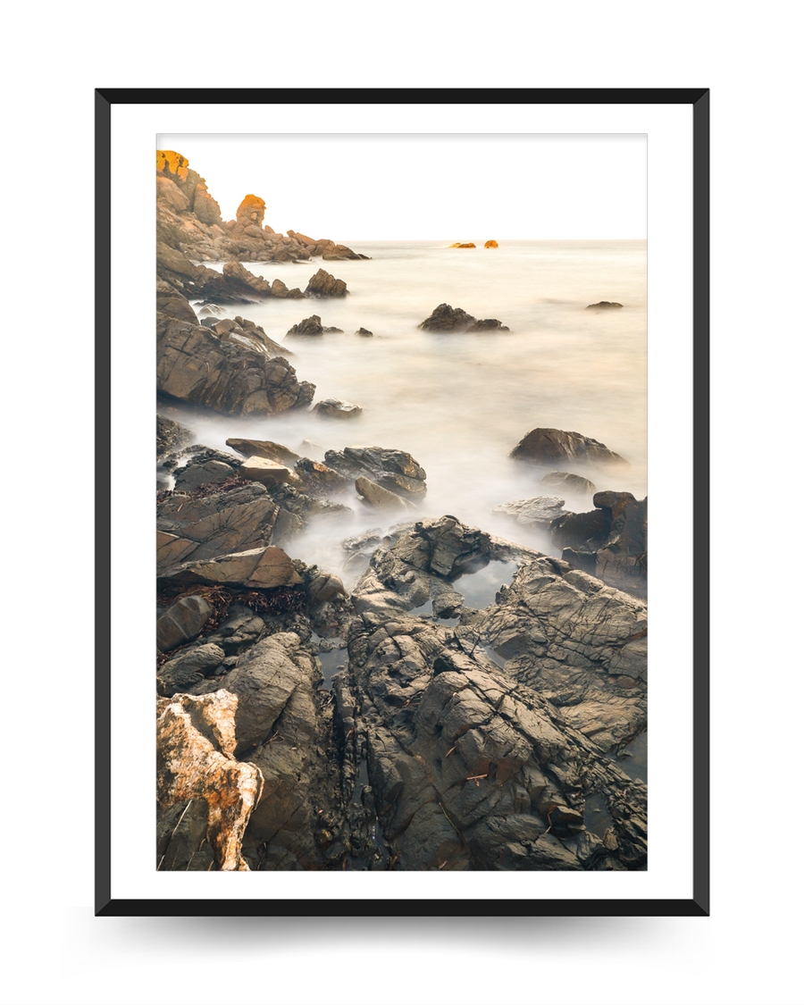 A poster of a Rocky coastline with misty water and soft light