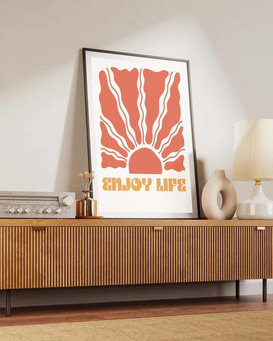 A poster of sunshine rays and written words that says Enjoy Life placed on a brown table