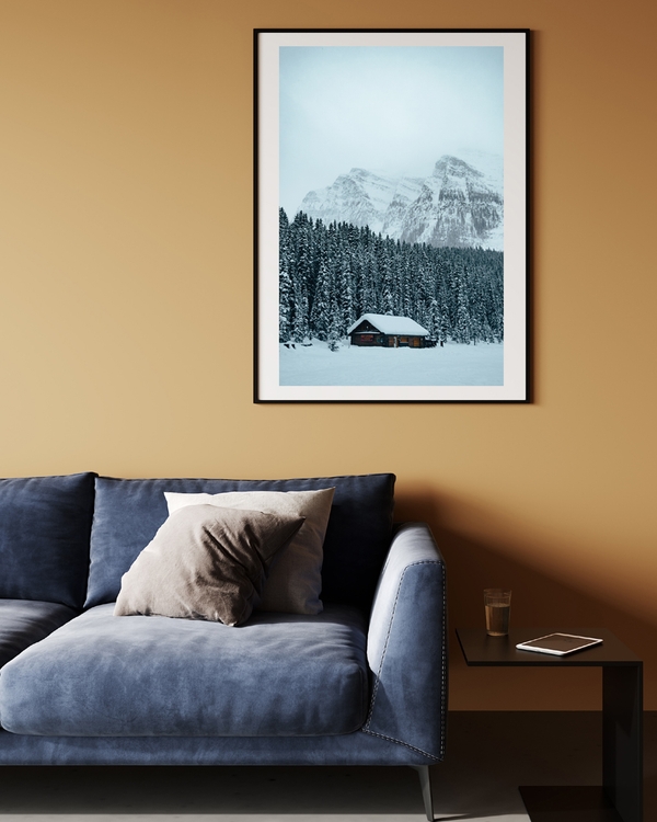 A poster of a Snow-covered cabin surrounded by pine trees and mountains