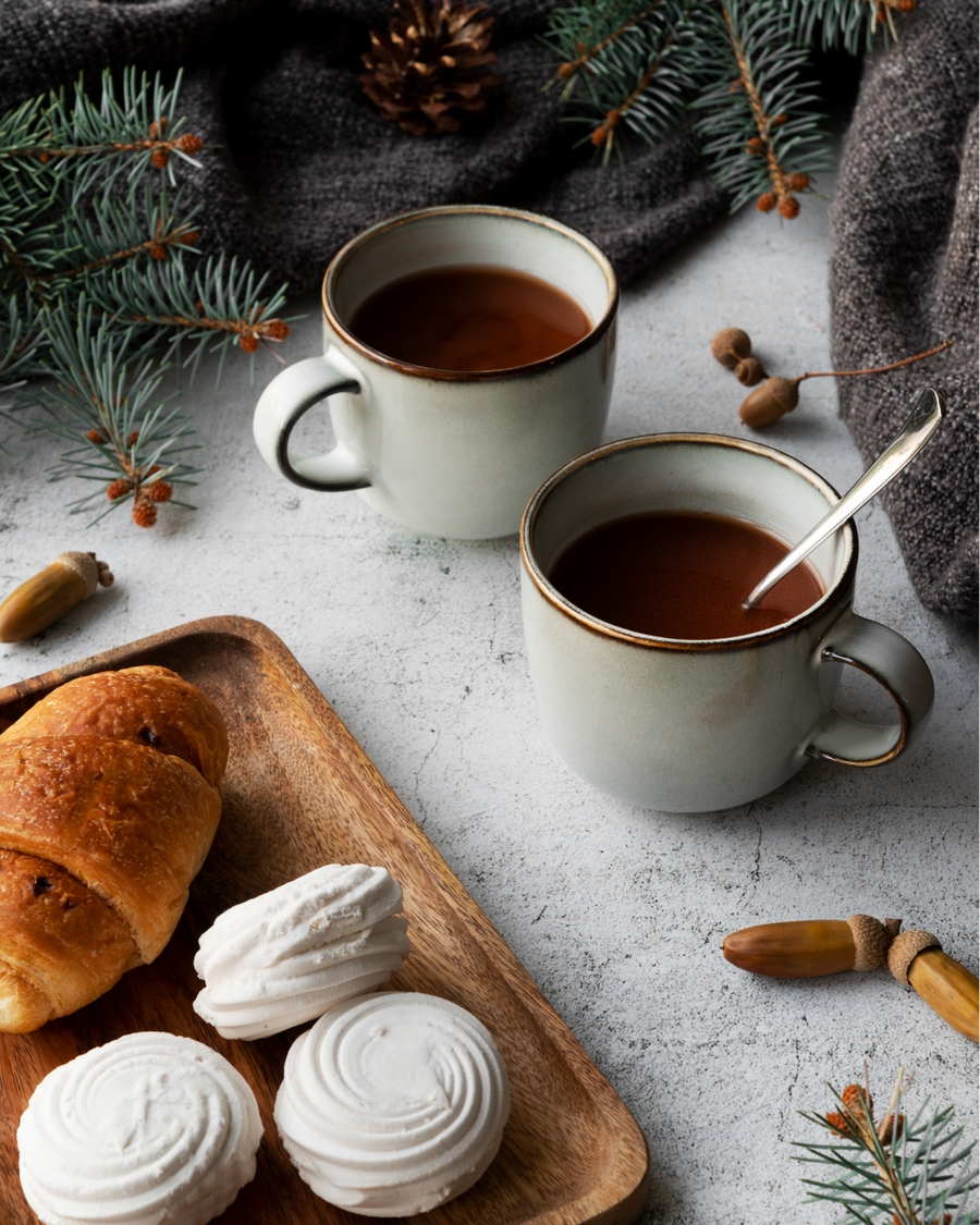 Two cups of hot drink with pastries and meringues