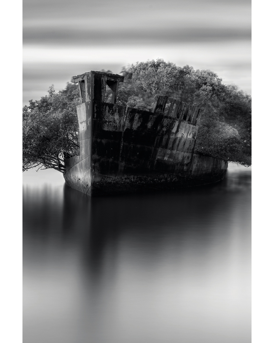Abandoned shipwreck reflected in calm monochrome water