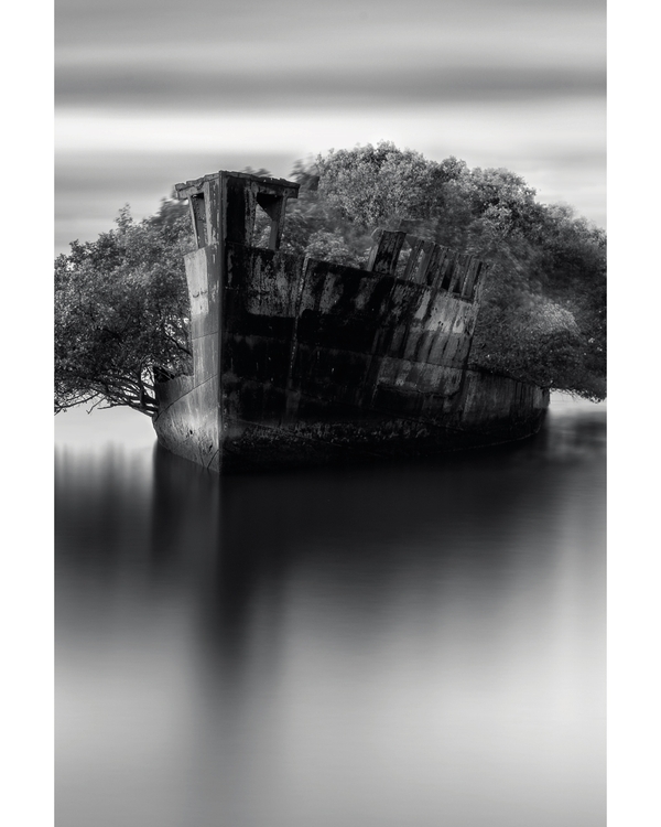 Abandoned shipwreck reflected in calm monochrome water