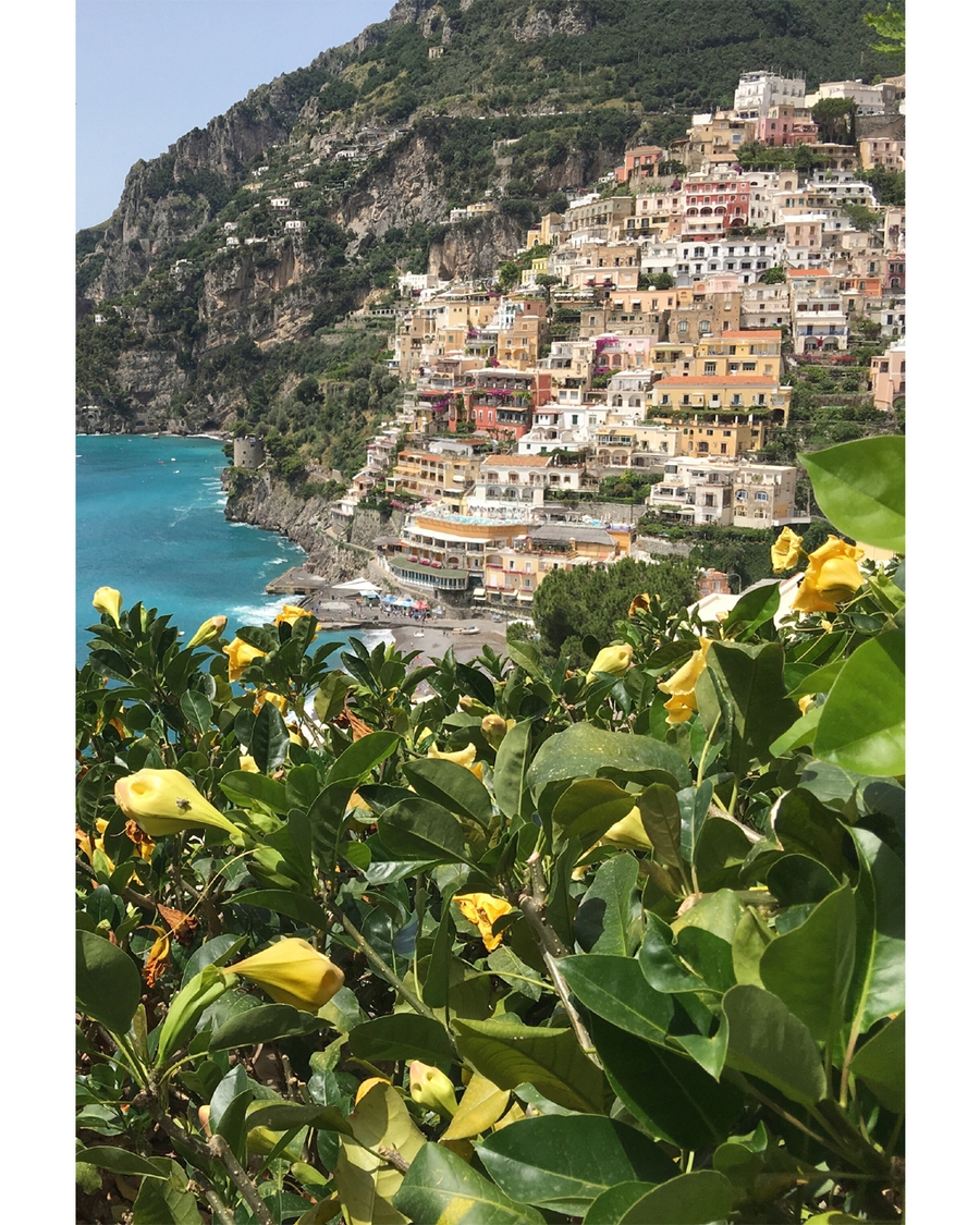 Colorful hillside village by turquoise sea and greenery