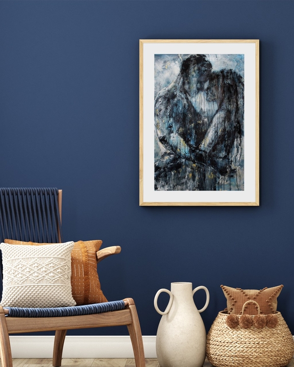 Blue Embrace poster in a light oak frame on a deep navy wall above a wooden lounge chair