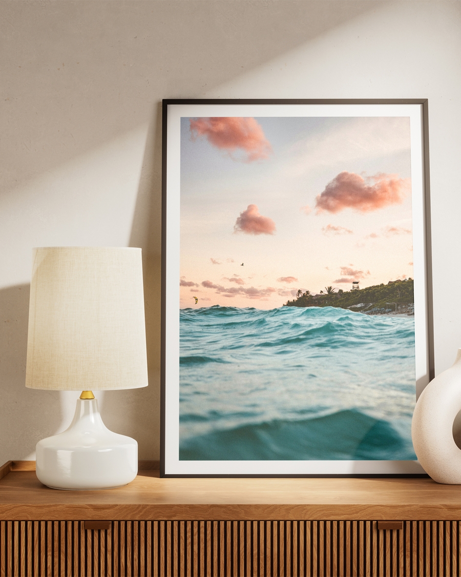 Poster of a clear sky with blue water places over a brown table next to a lamp