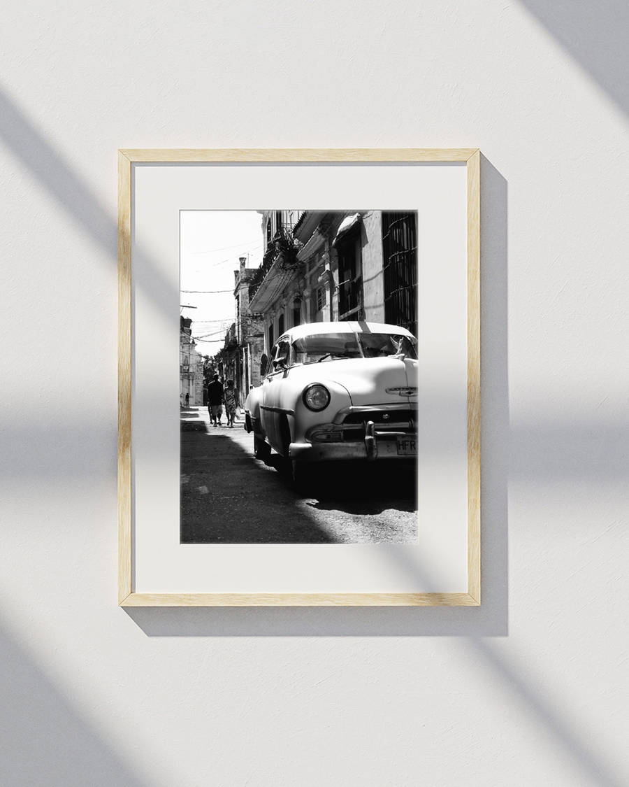 A poster of a Classic car parked on narrow street with old buildings