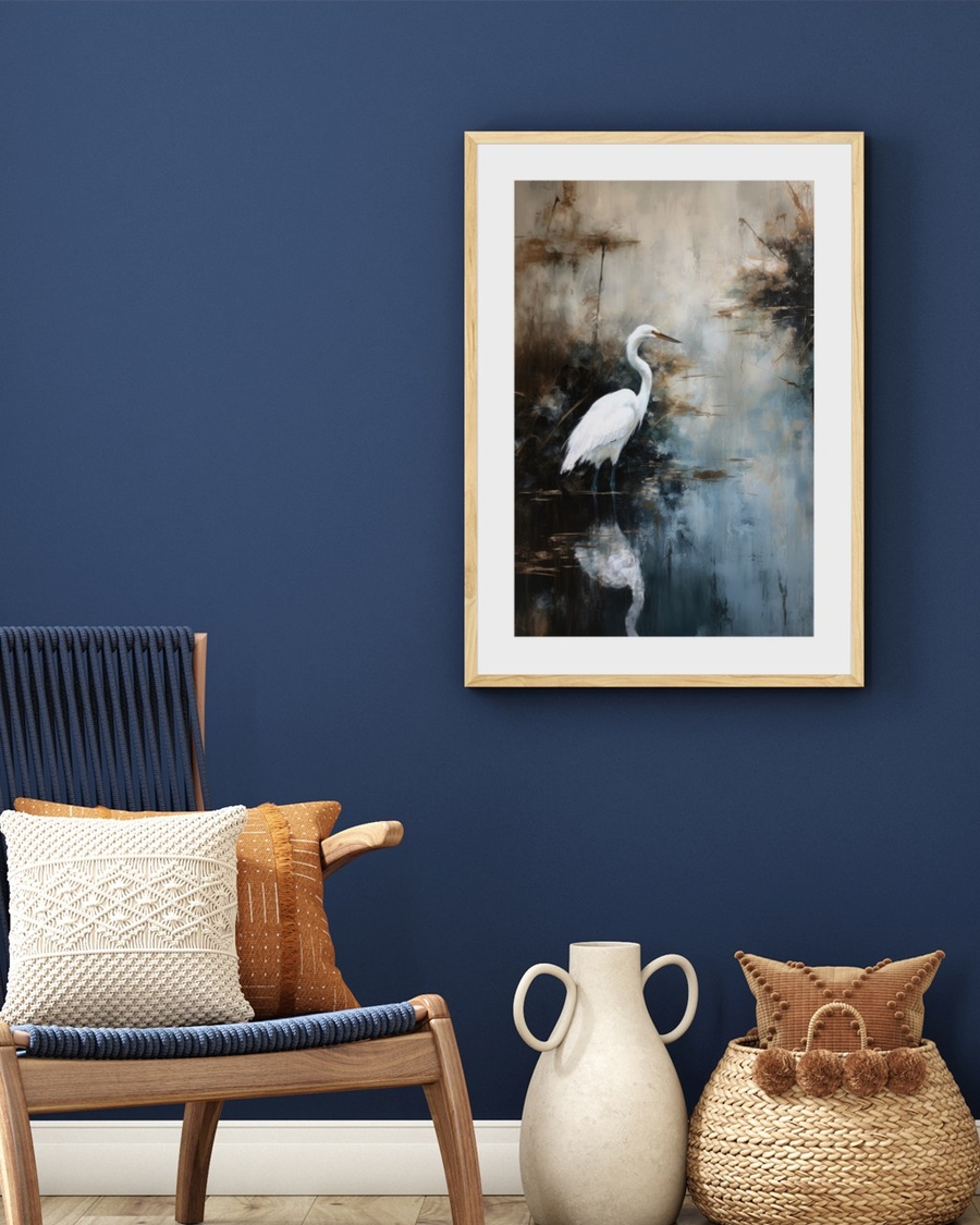Egret in Mist poster in a light oak frame on a deep navy wall above a wooden lounge chair