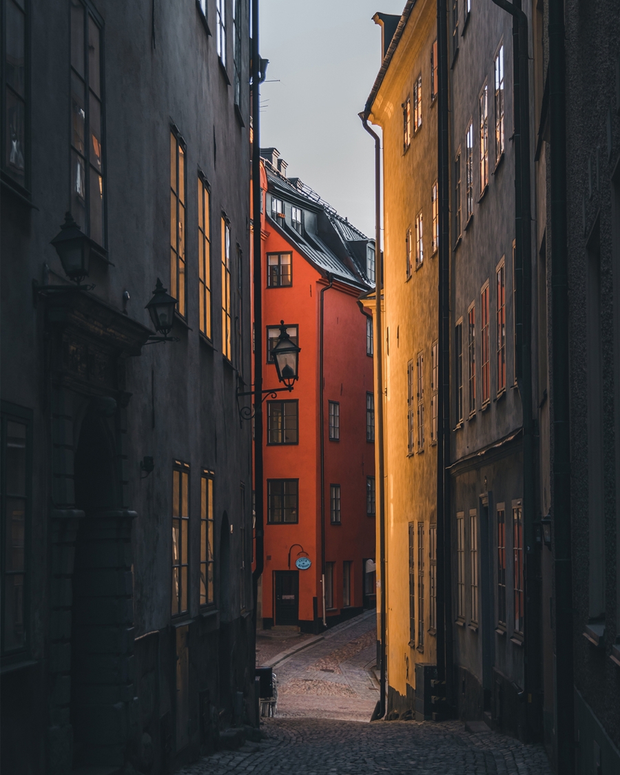 Narrow cobblestone alley with golden light and red house