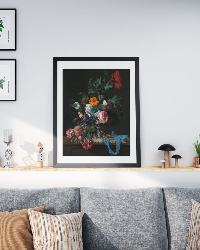 A framed poster of vintage painting of floral in placed on a shelf