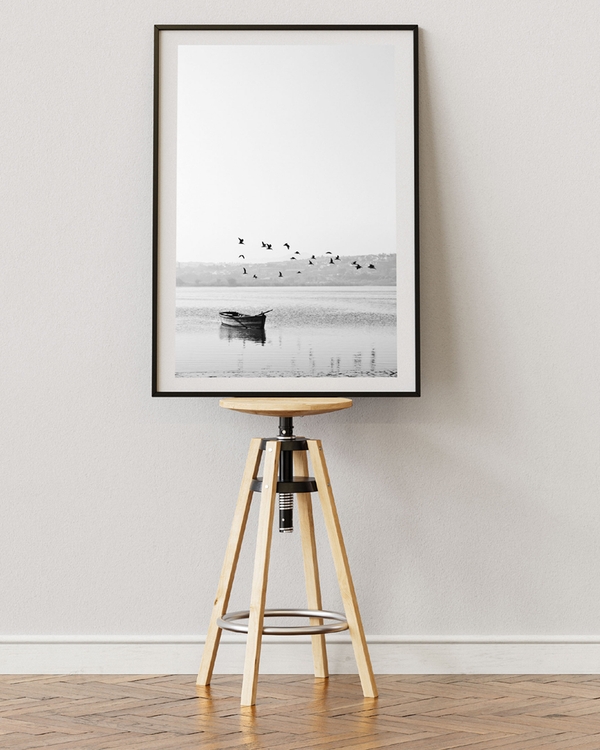 A poster of a black-and-white photo of a boat and flying birds over water