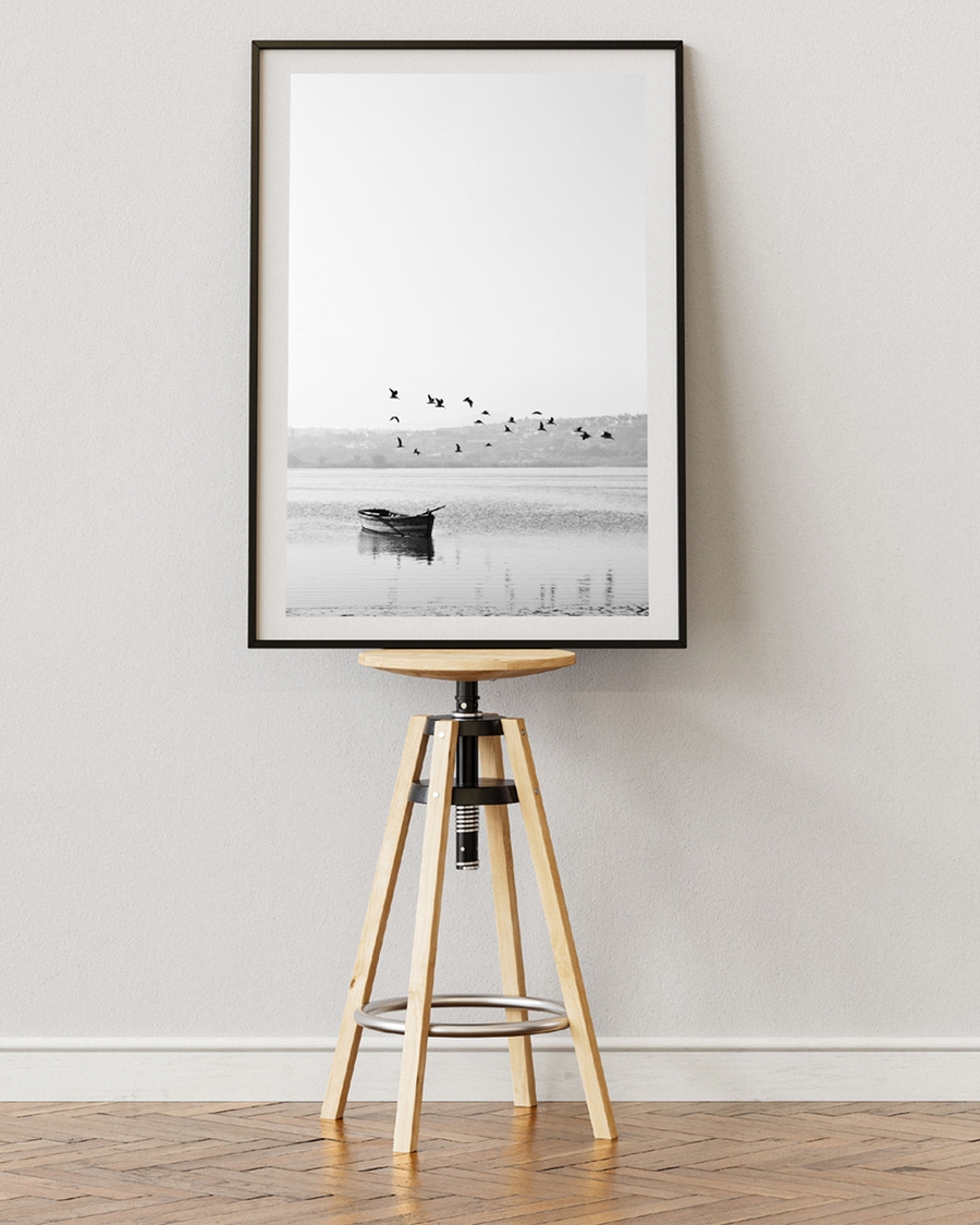 A poster of a black-and-white photo of a boat and flying birds over water