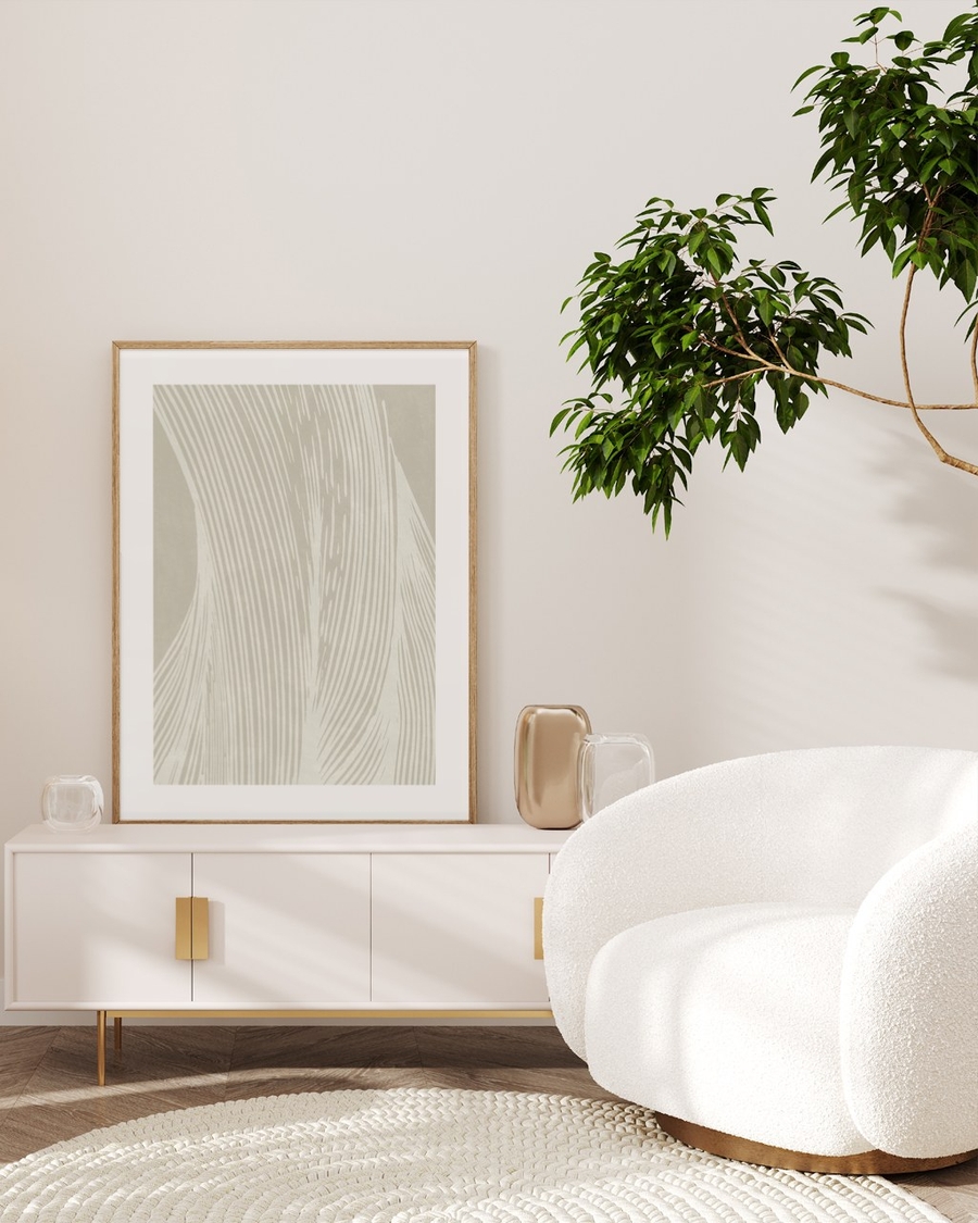 Sand Ripples poster in a light oak frame leaning on a white sideboard in a minimal living room