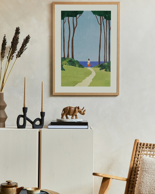Path to the Sea poster in a light oak frame above a white sideboard in a calm living room