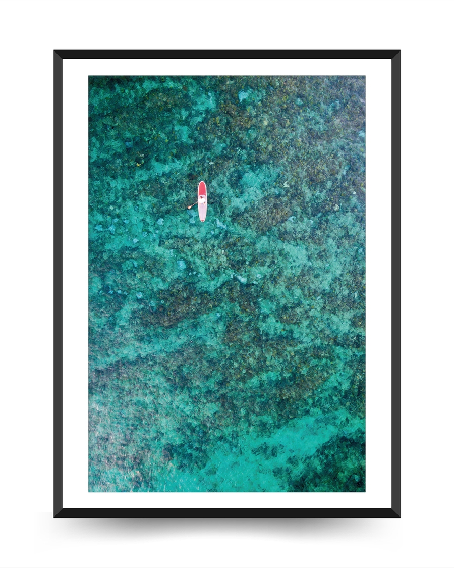 A poster of a Aerial paddleboarder floating above turquoise coral reef
