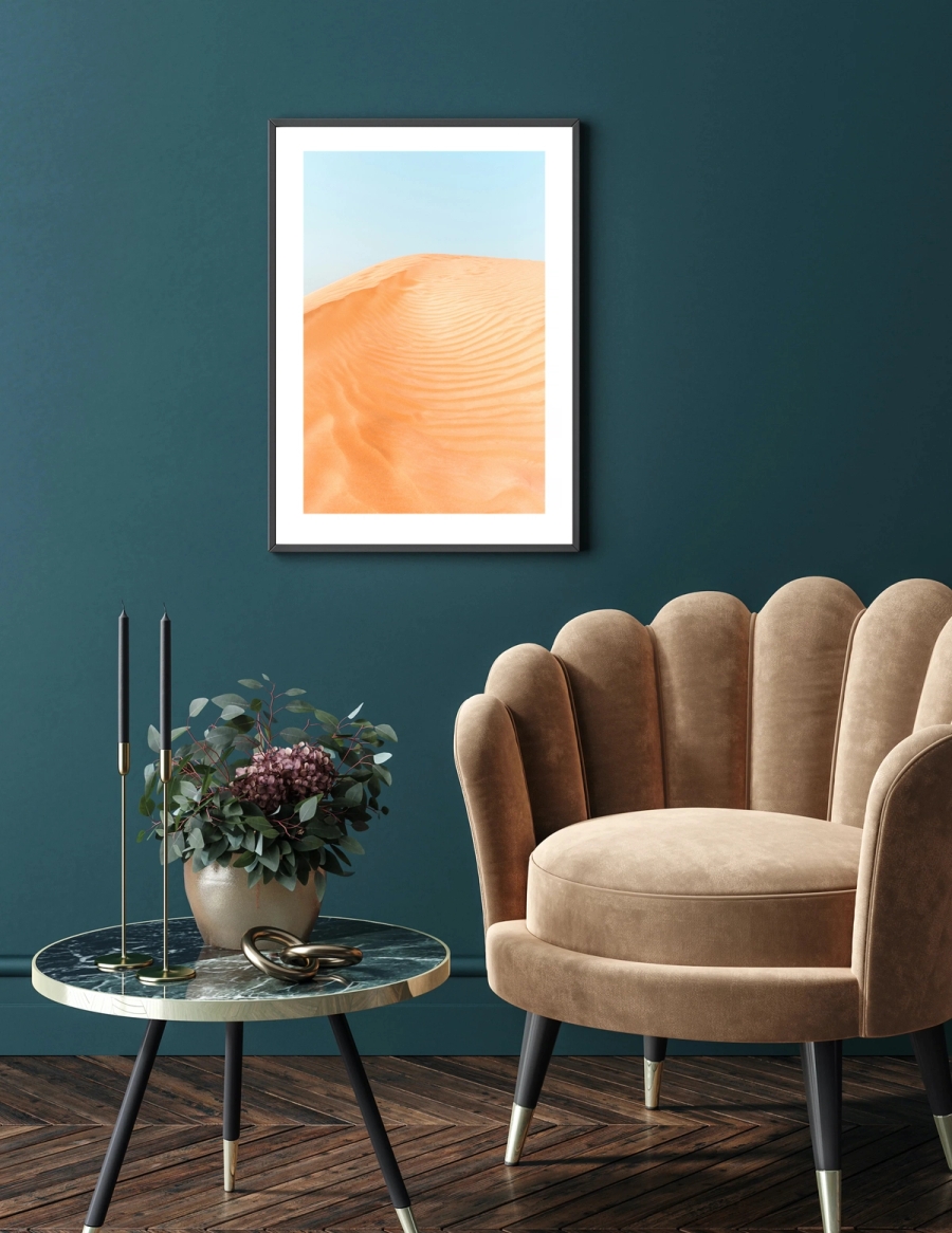 An orange desert with a blue sky poster hanged on a wall in a room with furniture.