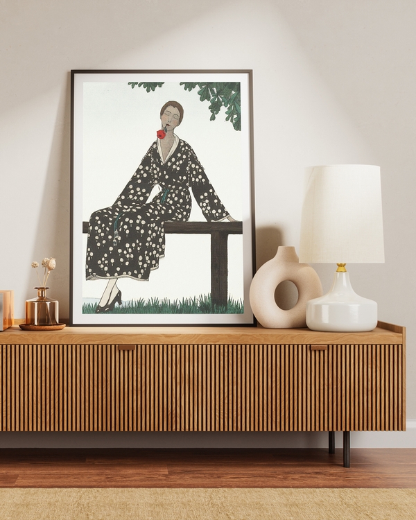 A poster of a woman in a black and white floral robe sitting on a brown bench placed on brown table