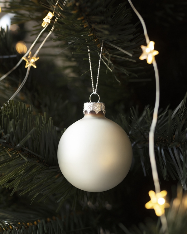 White Christmas ornament hanging on tree with star lights
