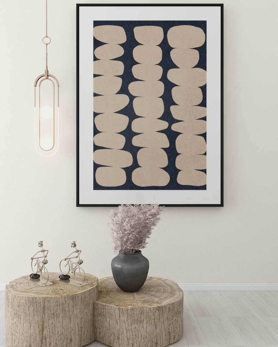 Stacked Sand Forms poster in a slim black frame above rustic wood stump tables in a bright hallway