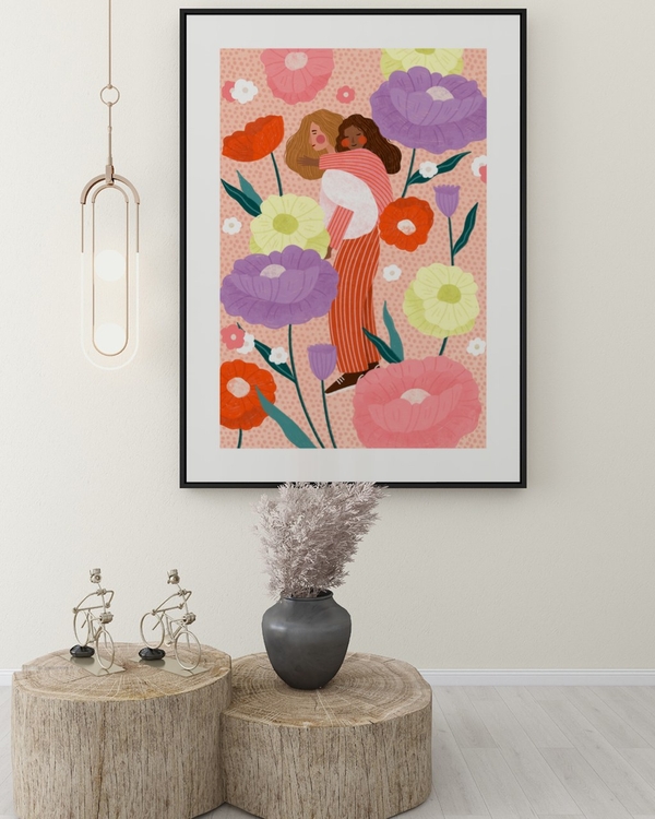 Embrace in Bloom poster in a slim black frame above rustic wood stump tables in a bright hallway
