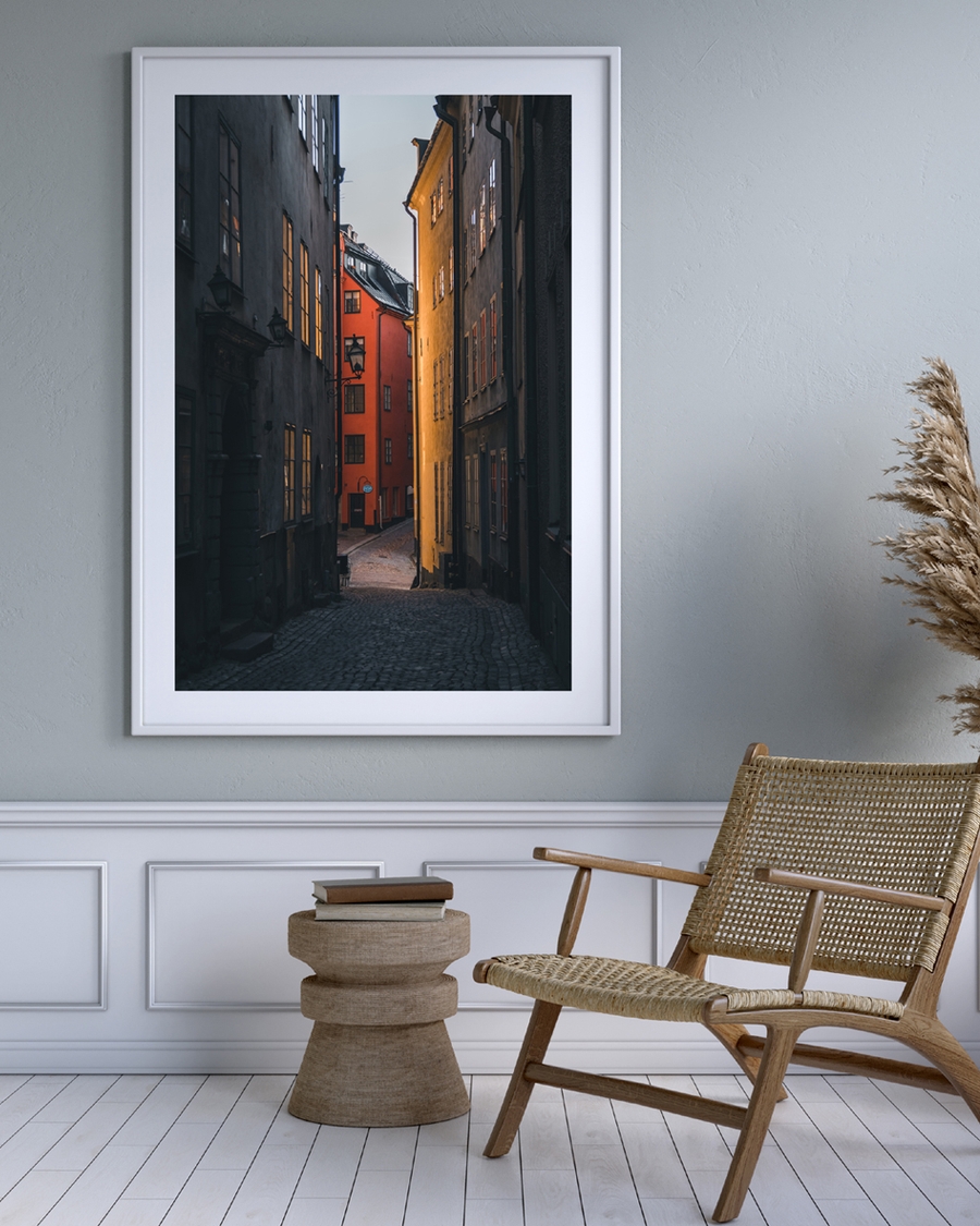 A poster of a Narrow cobblestone alley with golden light and red house