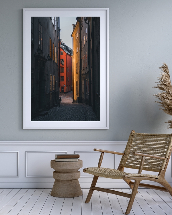 A poster of a Narrow cobblestone alley with golden light and red house