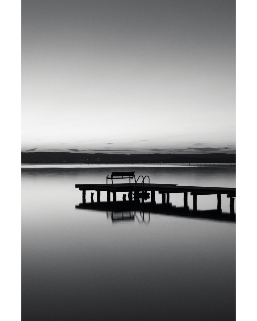 Pier reflected in calm water at dusk
